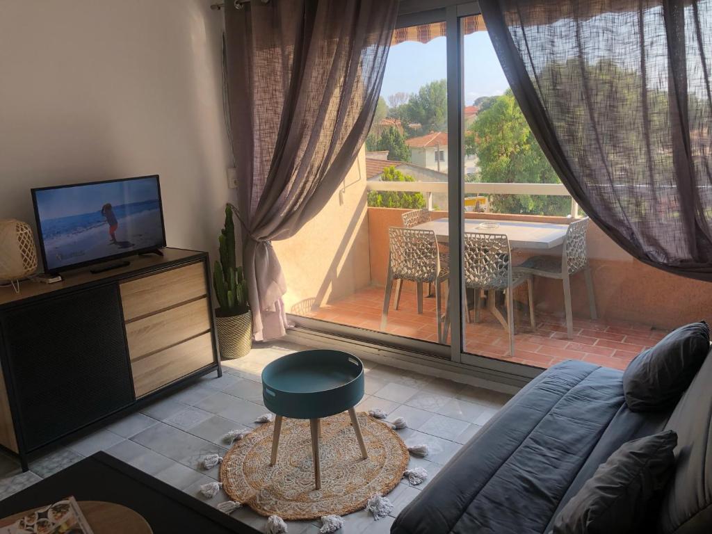 Il comprend un salon avec un canapé, une télévision et un balcon. dans l'établissement Appart. F2 apercu Port de Santa Lucia St Raphaël, à Saint-Raphaël