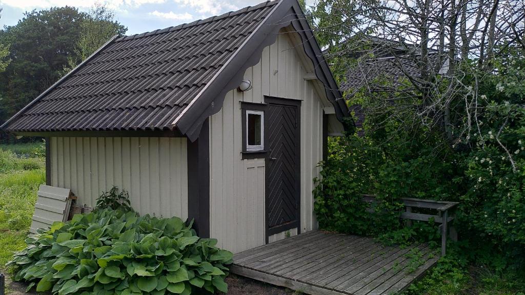 a small building with a wooden porch and a bench at Lilla mysstuga i havsnära in Varberg