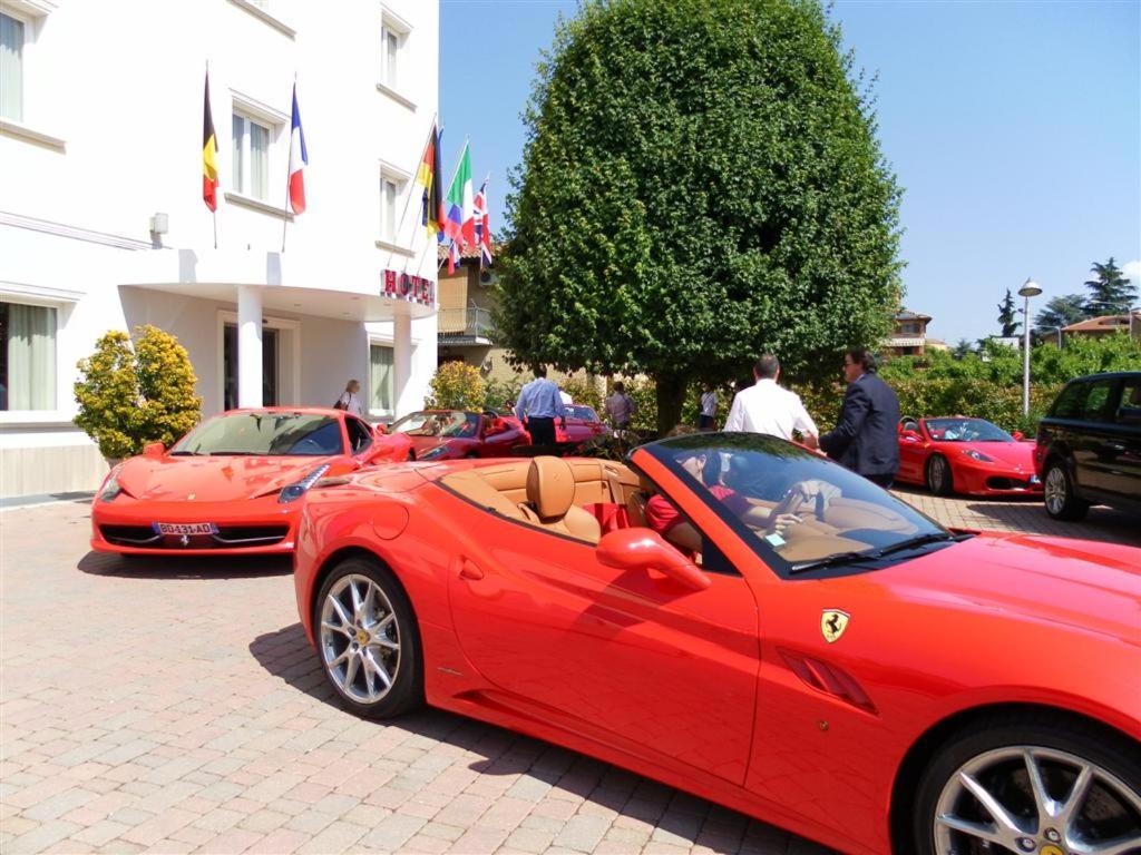 een groep rode auto's geparkeerd op een parkeerplaats bij Hotel Arthur in Solignano Nuovo