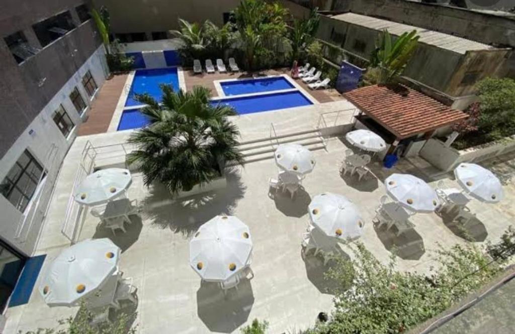 an aerial view of a patio with umbrellas and a pool at Guarujá Pitangueiras Flat Capitania Varam in Guarujá