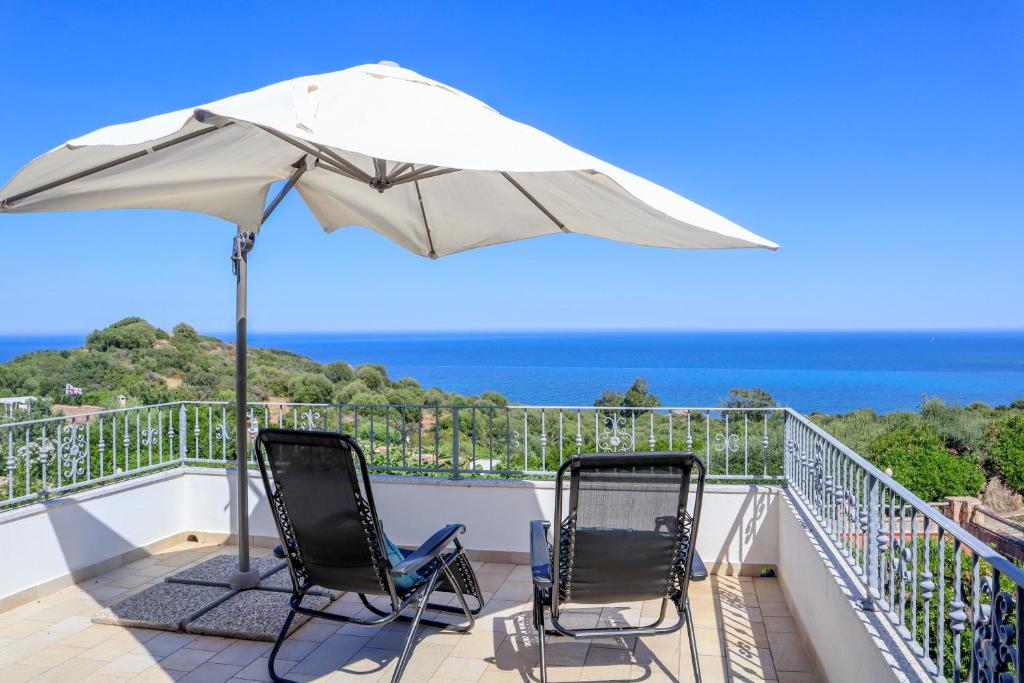 zwei Stühle und ein Sonnenschirm auf einem Balkon mit Meerblick in der Unterkunft Apartment Azzuro Porto Ottiolu in Porto Ottiolu