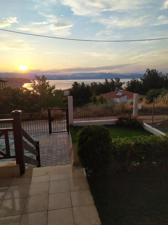 una puesta de sol sobre un patio con una valla en Afrodites sea view house, en Nea Roda