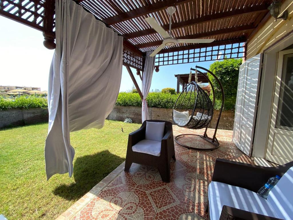 a porch with a swing and a chair on a patio at Chalet with backyard in North Coast near Marina & New Alamein الساحل الشمالي العلمين in El Alamein