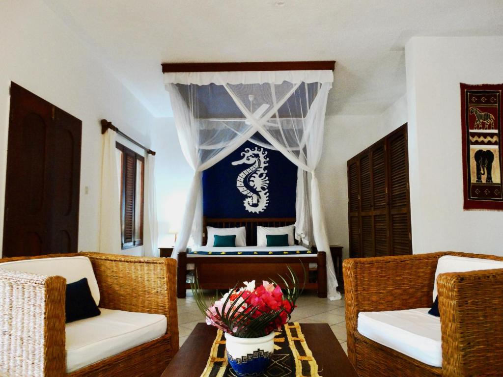 a living room with a table and chairs and a bed at Diani Cottages in Diani Beach