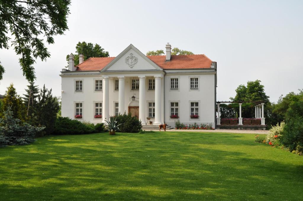 ein großes weißes Haus mit einem großen Hof in der Unterkunft Restauracja - Hotel Pałacowa in Rogowo