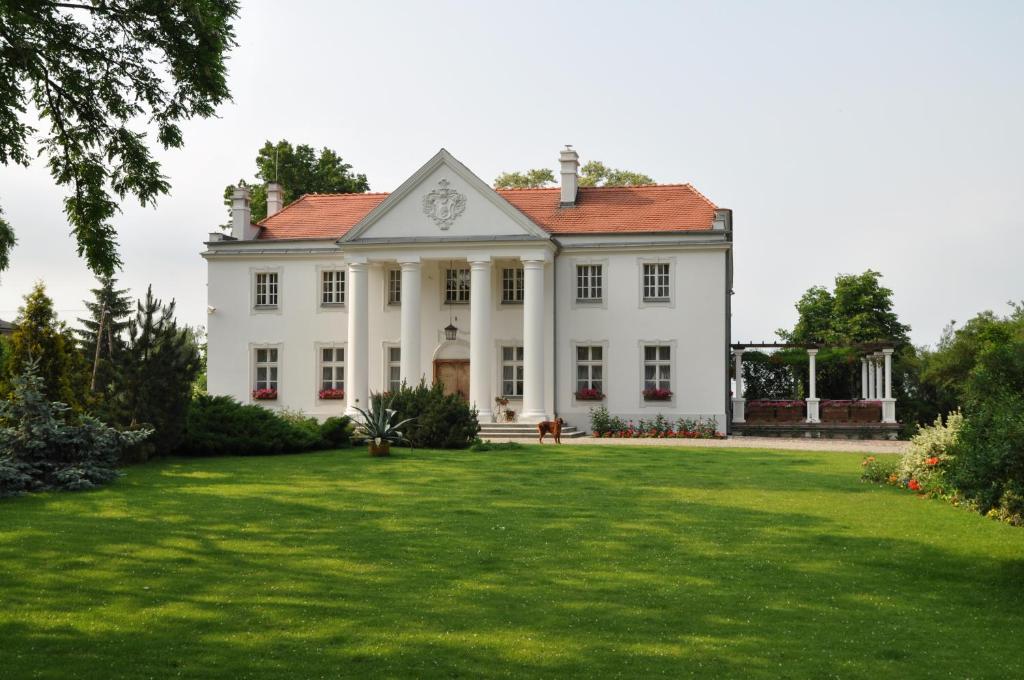 una gran casa blanca con un gran patio en Restauracja - Hotel Pałacowa en Rogowo