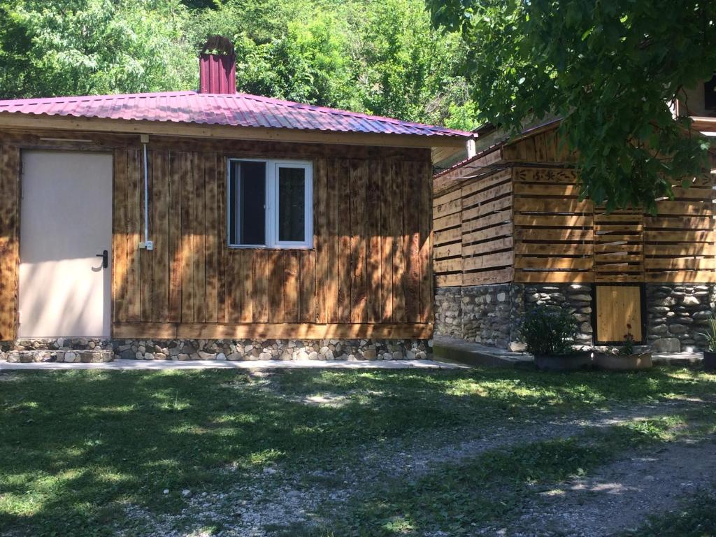 a log cabin with a white door and a window at Sunset Krikhi in Ambrolauri