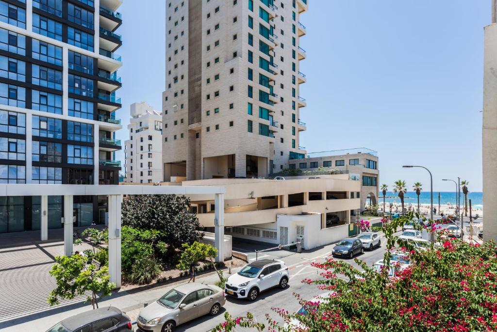 a parking lot with cars parked in front of tall buildings at Sweet Home On The Beach in Tel Aviv