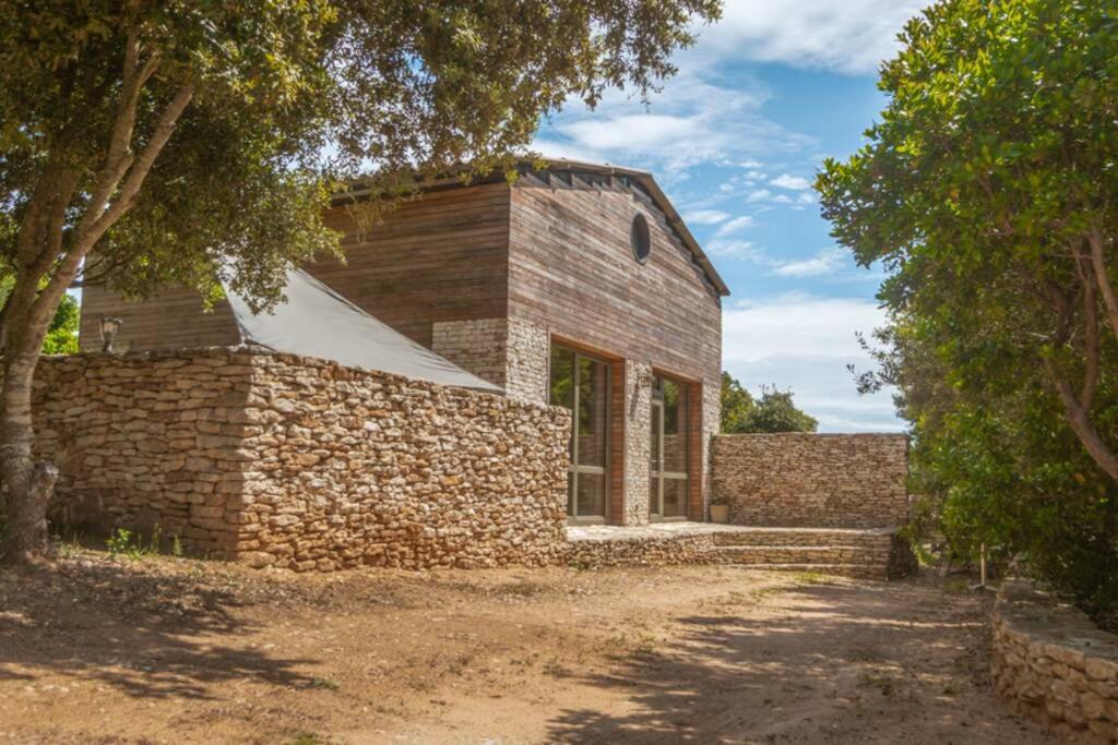 uma casa de tijolos com uma parede de pedra e árvores em Charmante Villa »InDa » em Bonifacio