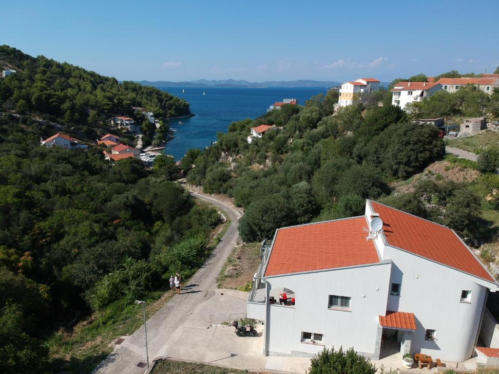 a house with a red roof on a hill next to the water at Apartments Sandro in Sali