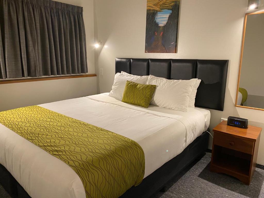 a bedroom with a large bed with a black headboard at ASURE Townsman Motor Lodge in Invercargill