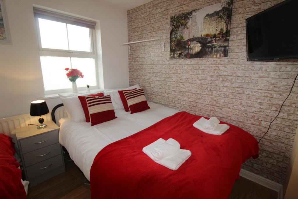 a bedroom with a red bed with towels on it at Harriers Grove House in Skegby