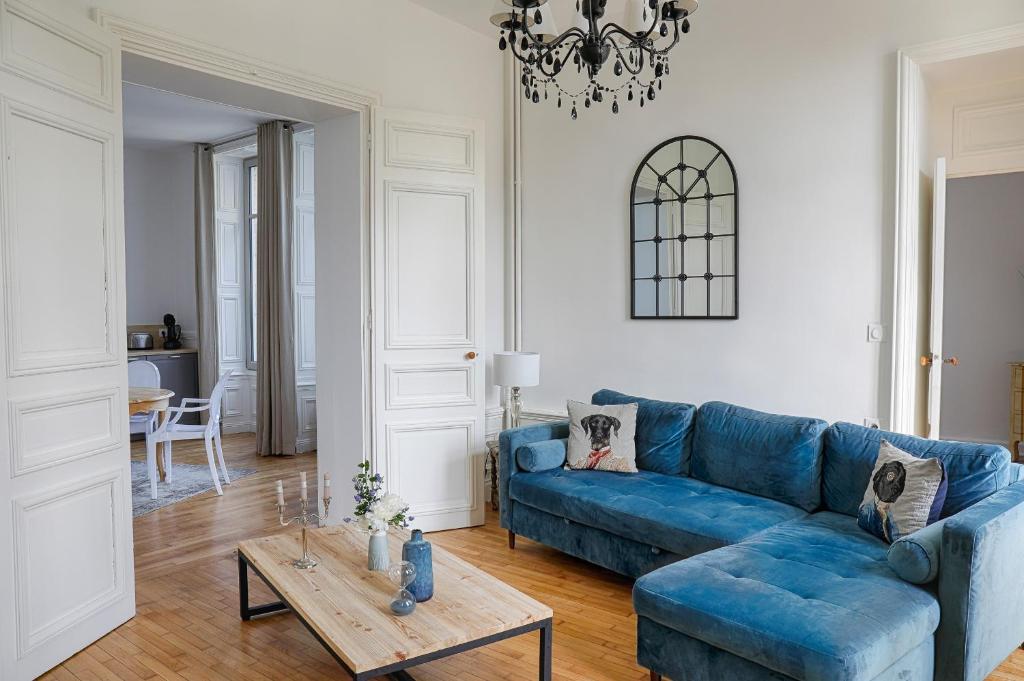 ein Wohnzimmer mit einem blauen Sofa und einem Tisch in der Unterkunft Résidence L'Aristide Appartement Louison in Auray