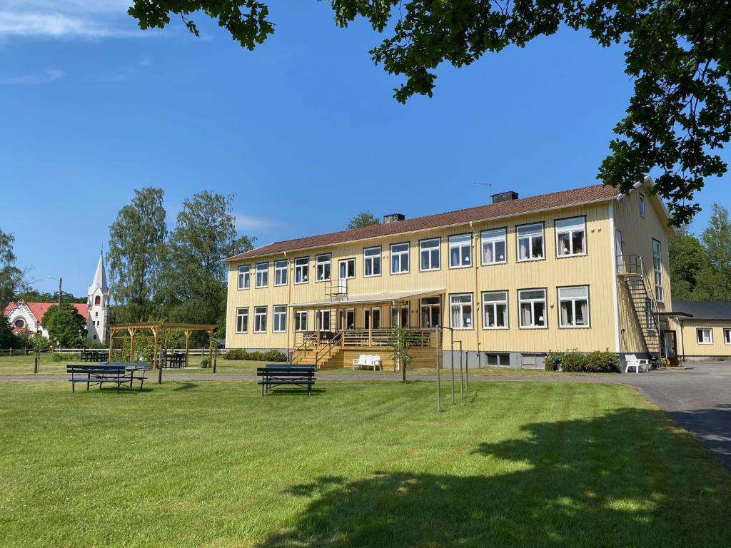 a large yellow building with benches in a park at Kalvs Skolhus in Kalv