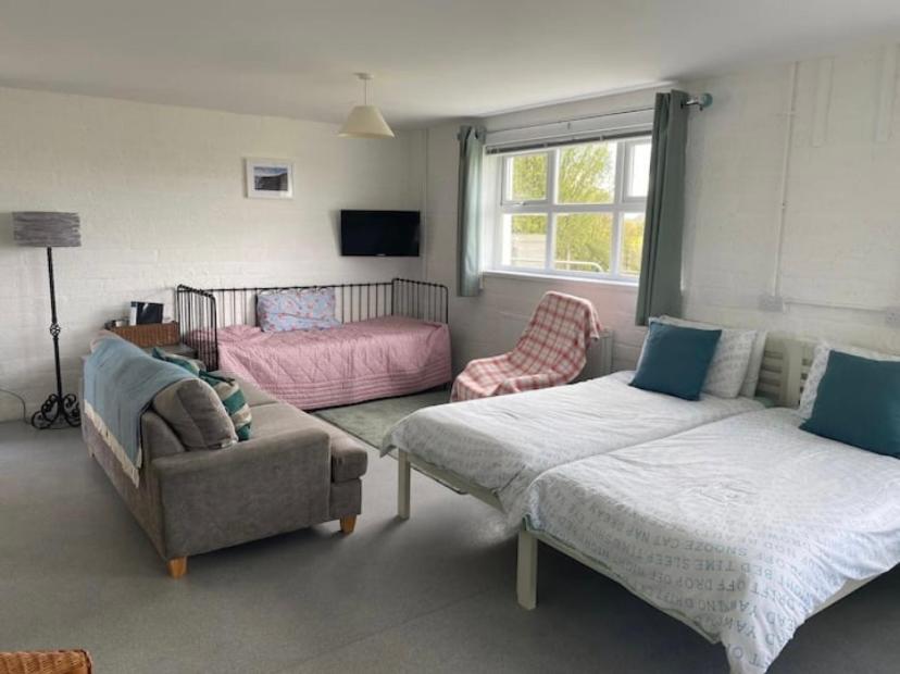 a living room with two beds and a couch at Mill House Studio Apartment in Stranocum