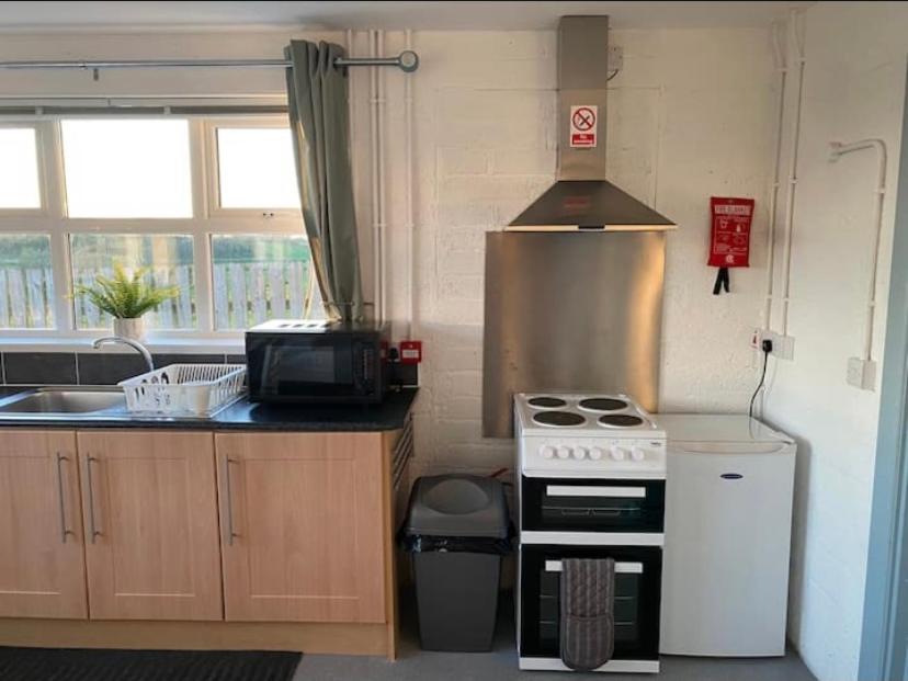 a small kitchen with a stove and a sink at Mill House Studio Apartment in Stranocum