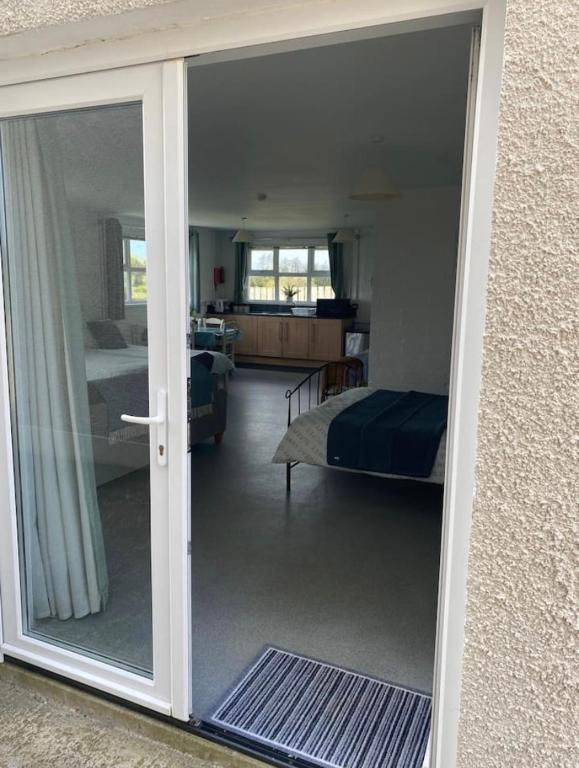 a sliding glass door to a bedroom with a bed at Mill House Studio Apartment in Stranocum
