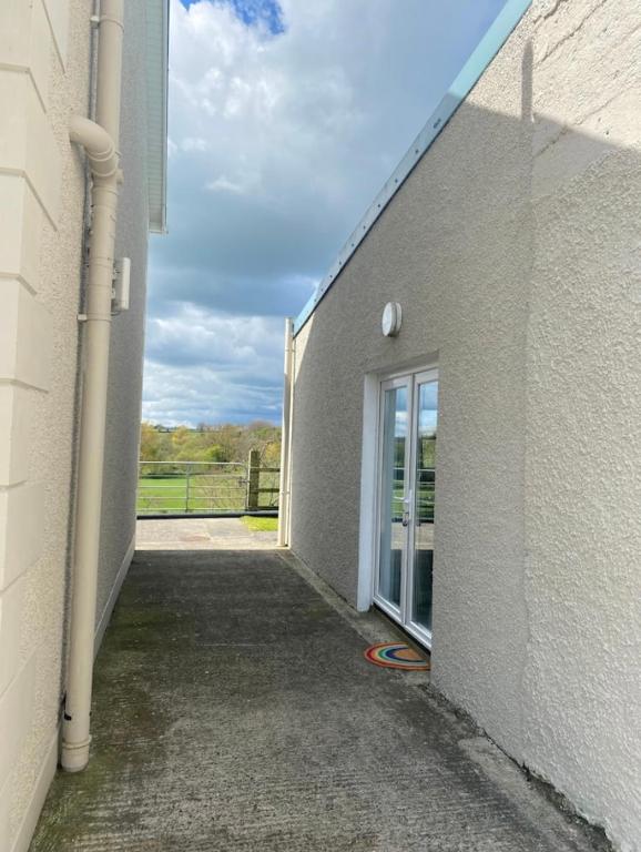 a white building with a door and a window at Mill House Studio Apartment in Stranocum