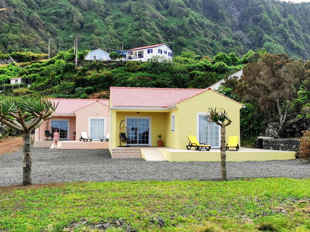 a yellow and pink house with a mountain in the background at Houses of Eira Velha in Fajã do Ouvidor