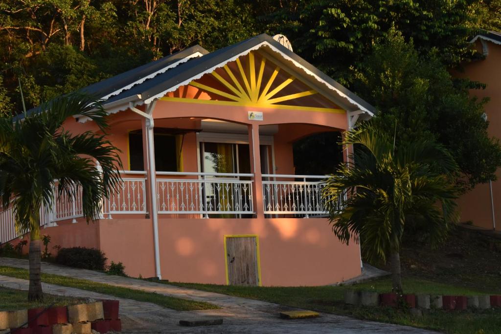 a small pink house with a porch and a balcony at Creole Nest in Pointe-Noire