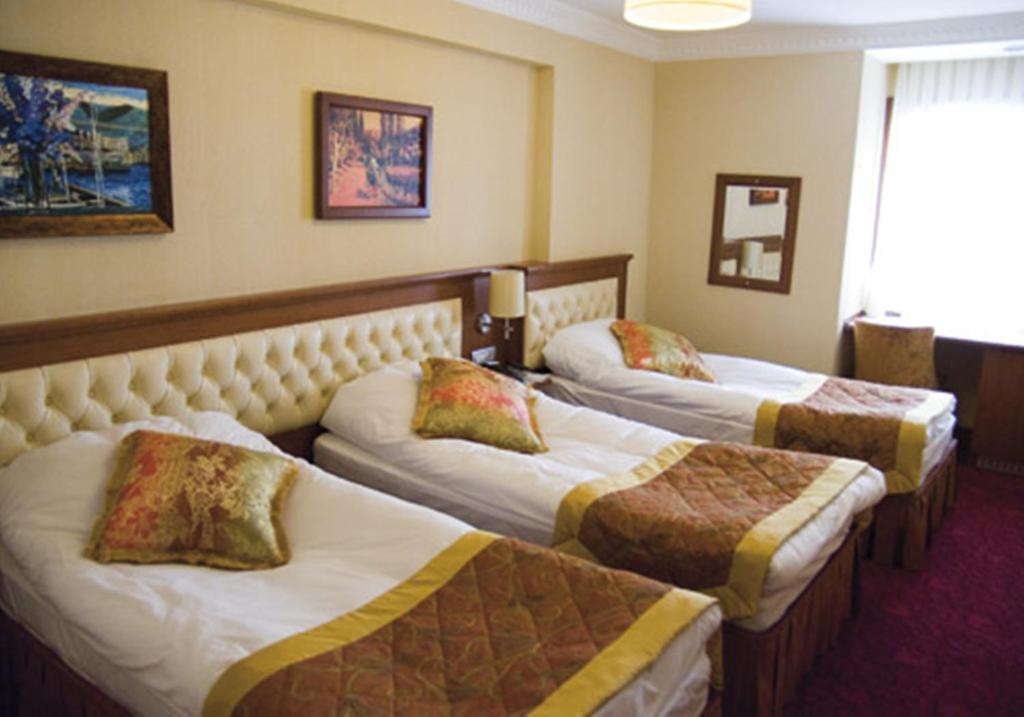 a hotel room with three beds with pillows on them at Hotel Linda in Istanbul