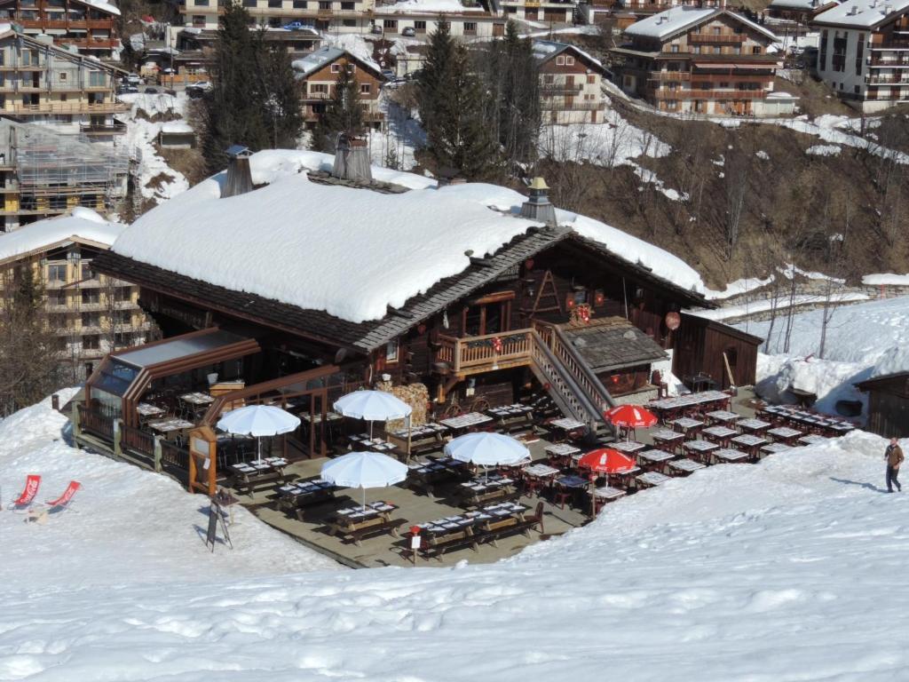 a ski lodge with tables and umbrellas in the snow at La Bournerie in Le Grand-Bornand
