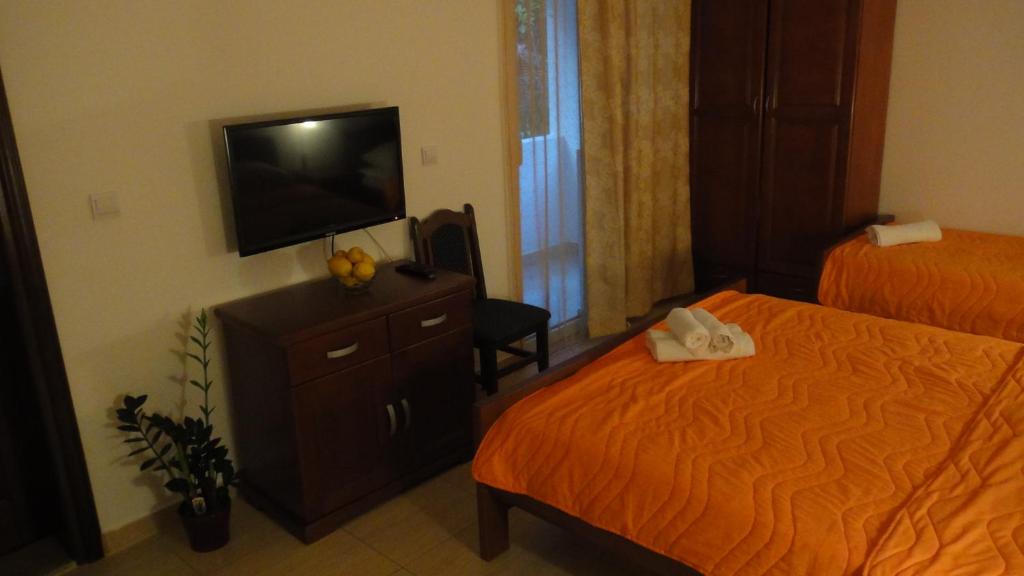 a hotel room with two beds and a flat screen tv at Apartmani More in Sveti Stefan