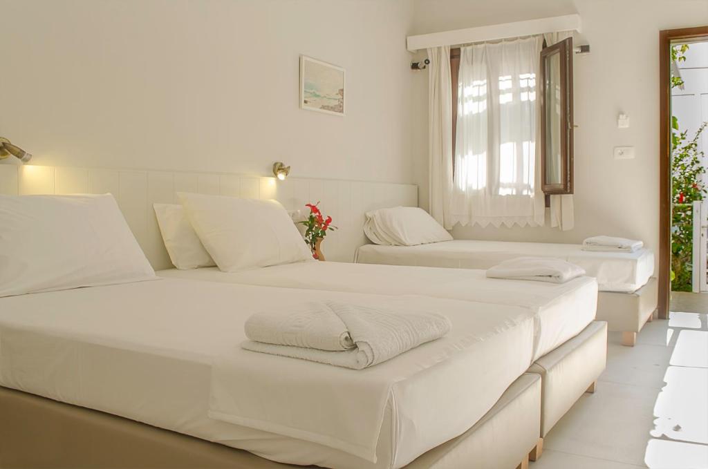 2 camas blancas en una habitación con ventana en Kalypso Studios & Rooms, en Palaiochóra