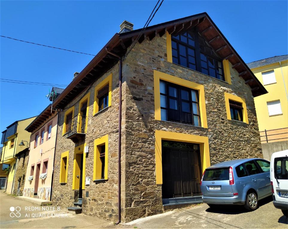 a stone building with yellow doors and windows at La obra de Joaquin, tu rincón en el Bierzo alto in Folgoso de la Ribera