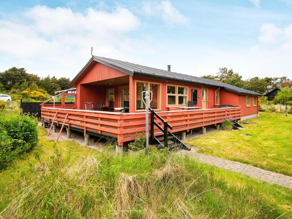 a red house with a black roof in a field at 6 person holiday home in Henne in Henne Strand