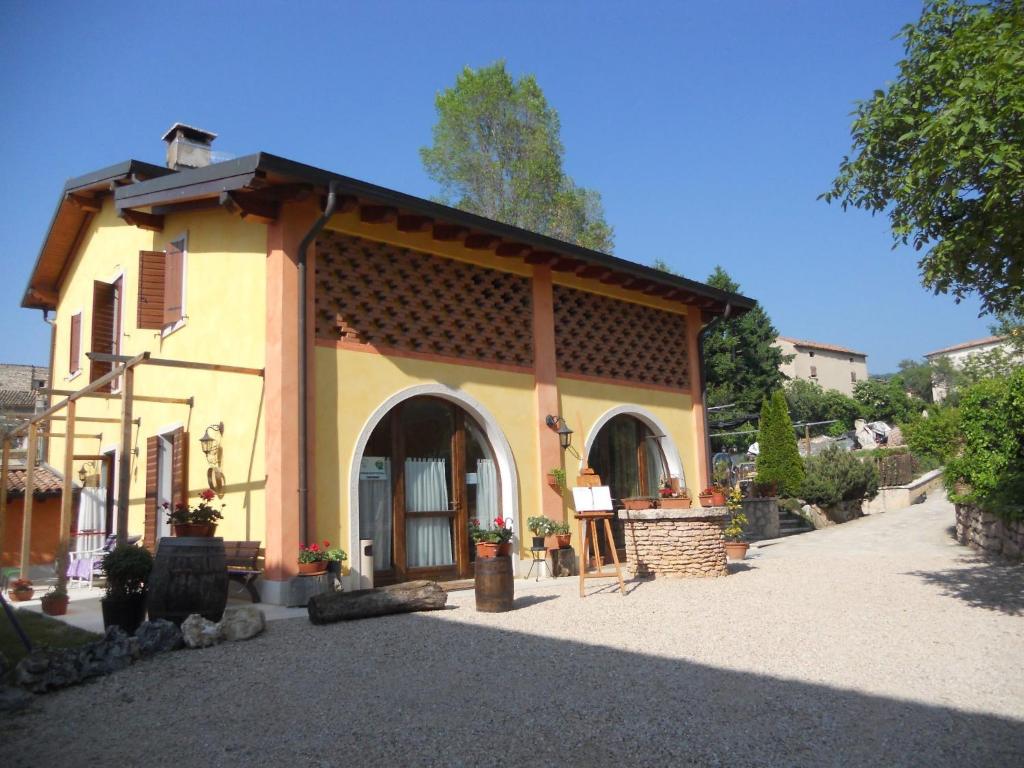 un pequeño edificio amarillo con porche en Le Bottesele, en San Zeno di Montagna