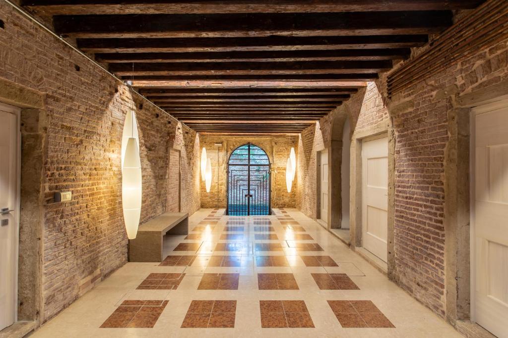 un pasillo vacío con paredes de ladrillo y una puerta en Palazzo Venere Apartments, en Venecia