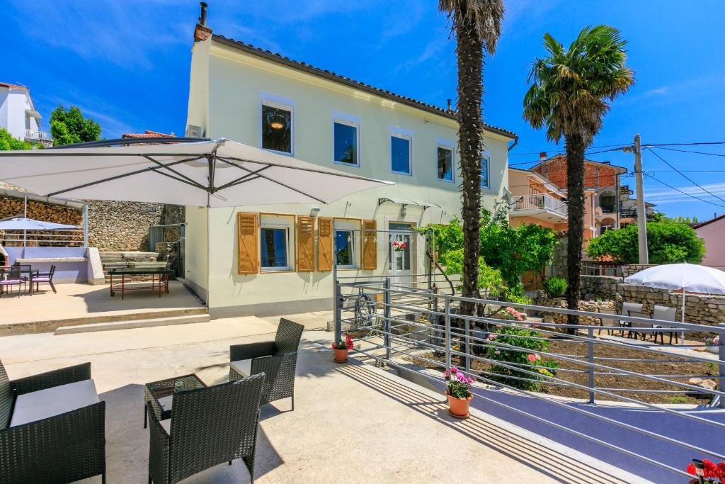 a house with a patio with chairs and an umbrella at House TINAC in Crikvenica