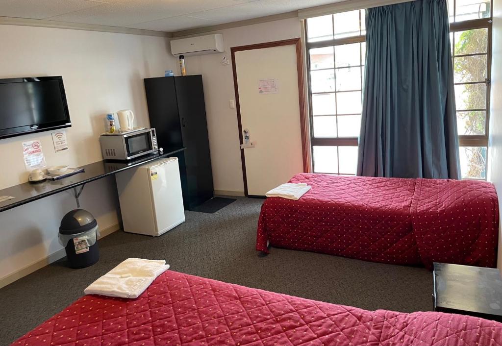a hotel room with two beds and a refrigerator at Paringa Hotel Motel in Renmark