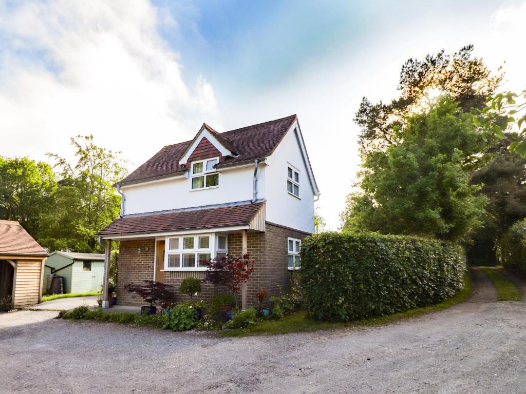 uma casa branca com um telhado preto em Wood Glen Cottage em Dallington