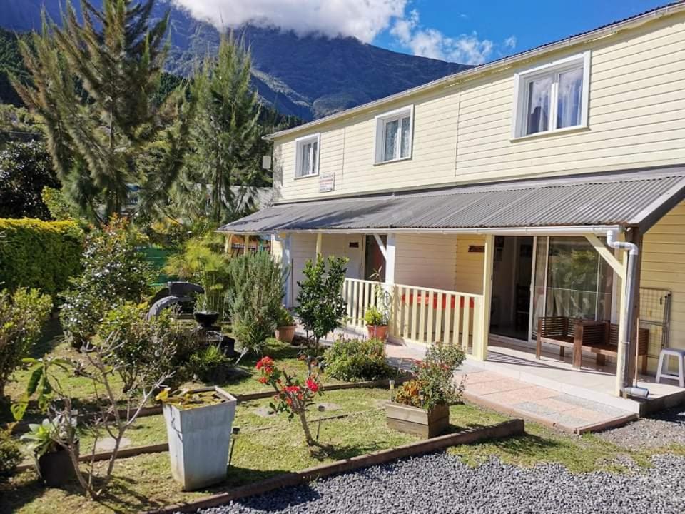 a house with a garden and mountains in the background at Les Jardins Créoles in Cilaos