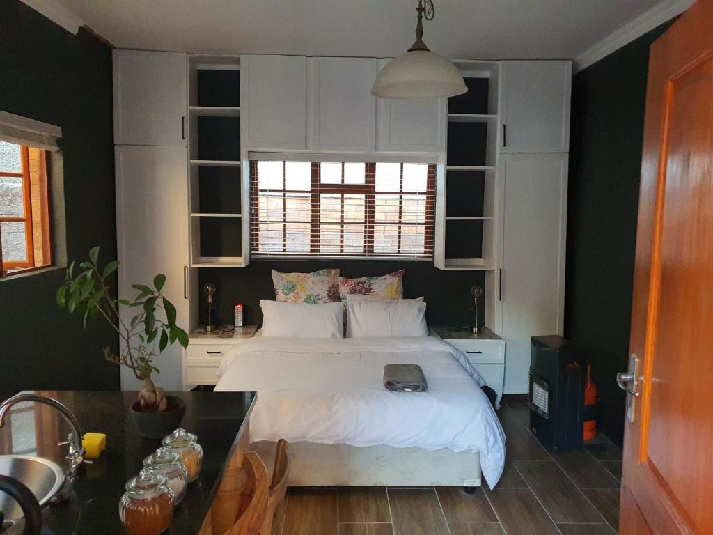1 dormitorio con cama blanca y mesa en Melvilla Studio, en Johannesburgo