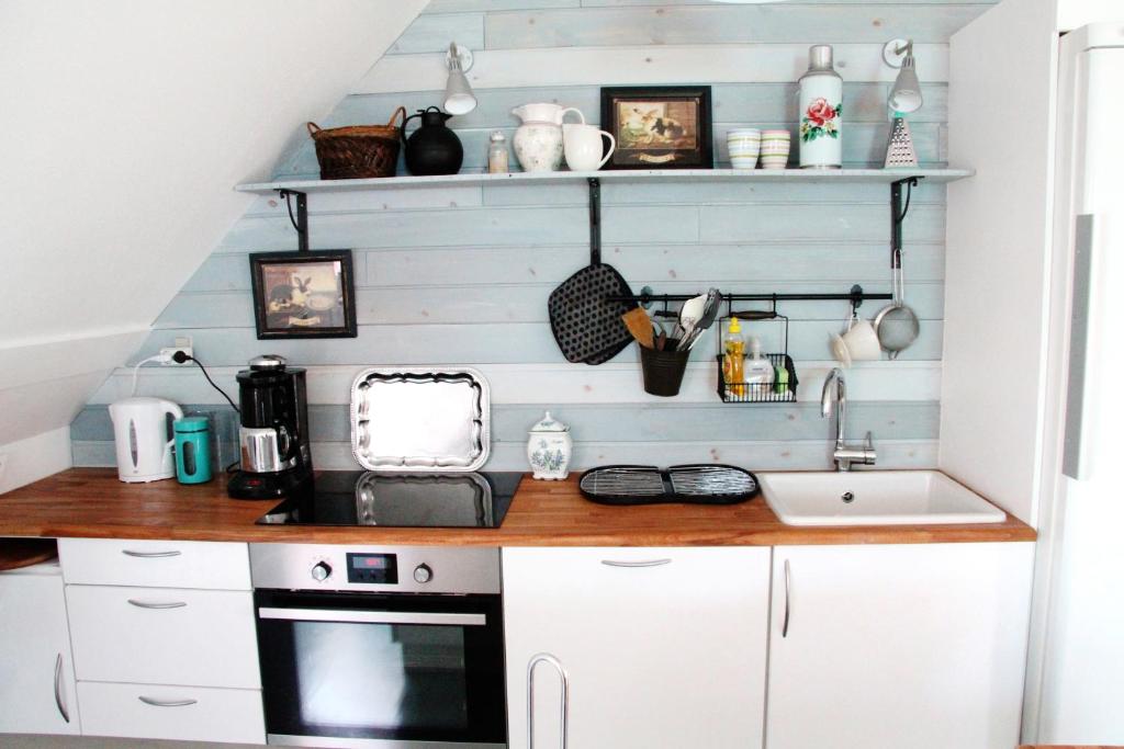 una cocina con armarios blancos y fregadero en Molevitten Apartments, en Søby