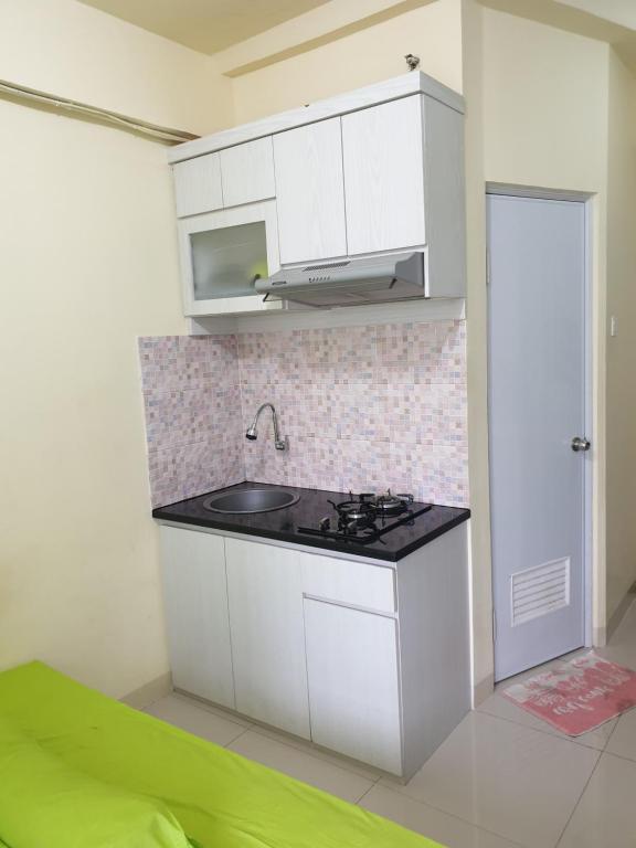 cocina con fregadero y fogones en una habitación en Properti9 at Apartemen Green Pramuka, en Yakarta