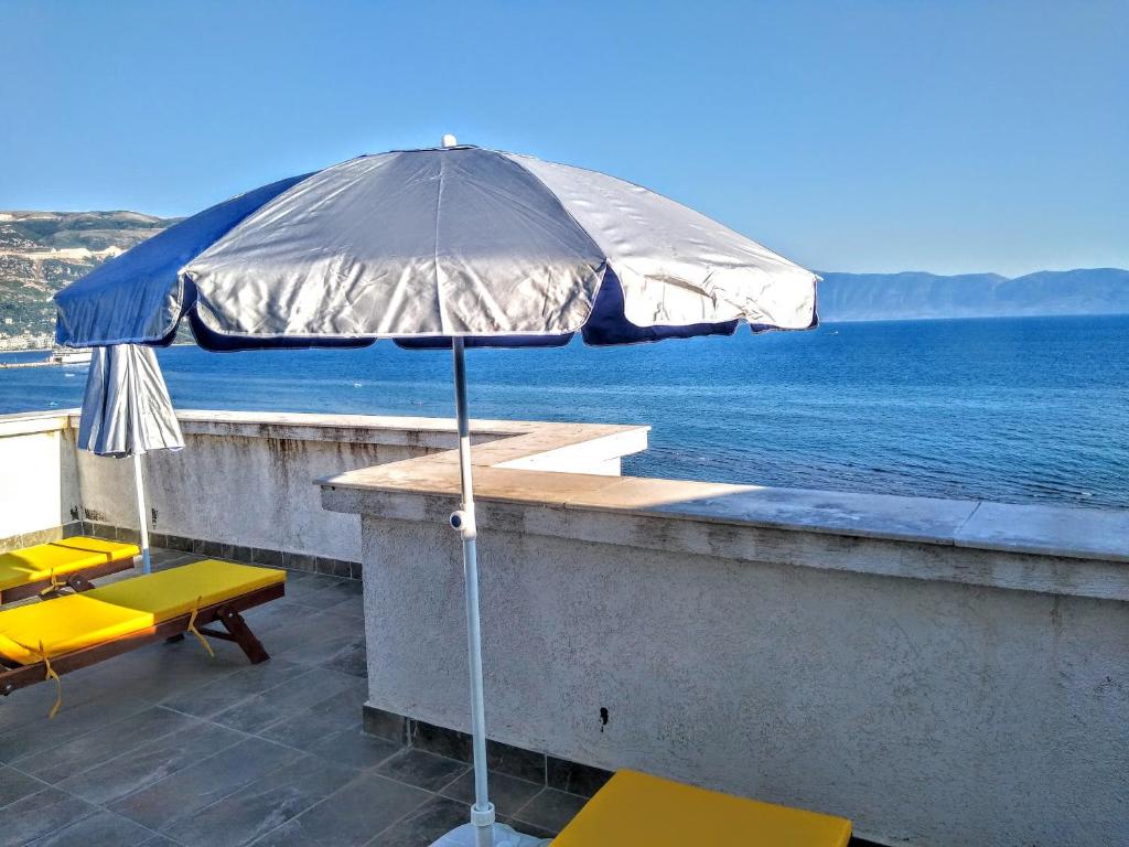 un ombrello seduto su un cornicione vicino all'acqua di Eirik's beachfront apartments & penthouse a Vlorë