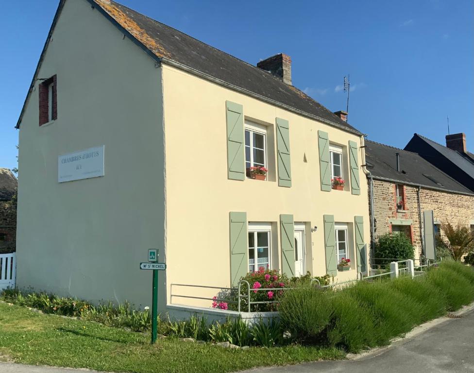 a white house with green shutters on a street at Les Voiles Vertes in Moidrey