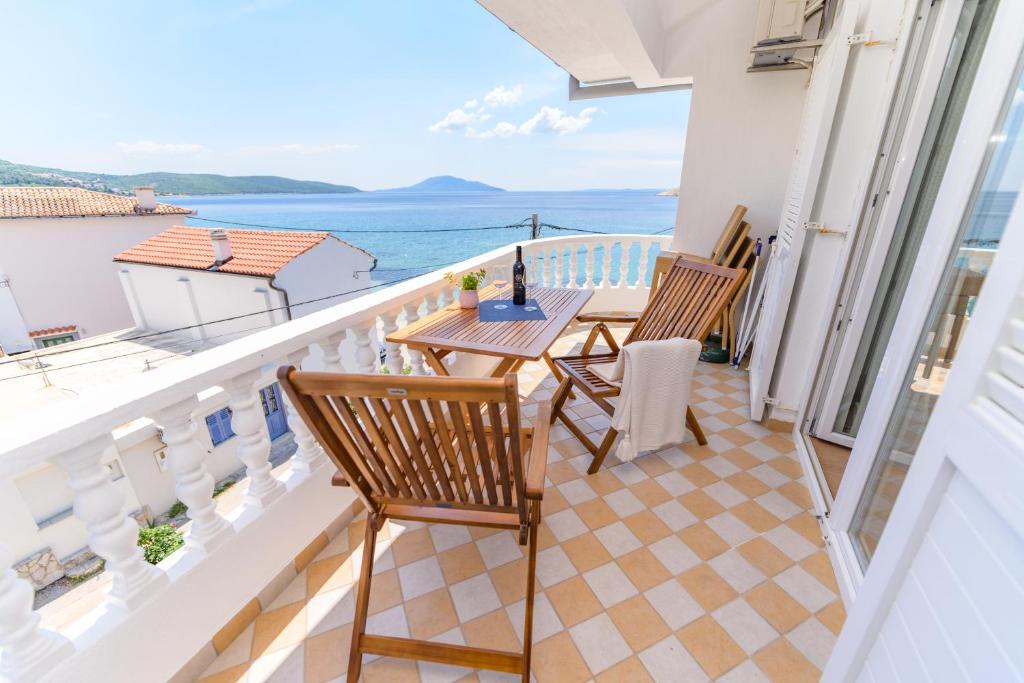 a balcony with a table and chairs and the ocean at Apartmani Noris (app2) in Martinšćica