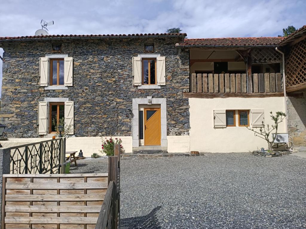 a stone house with a wooden fence in front of it at Cier De Riviere "les Ours" in Cier-de-Rivière