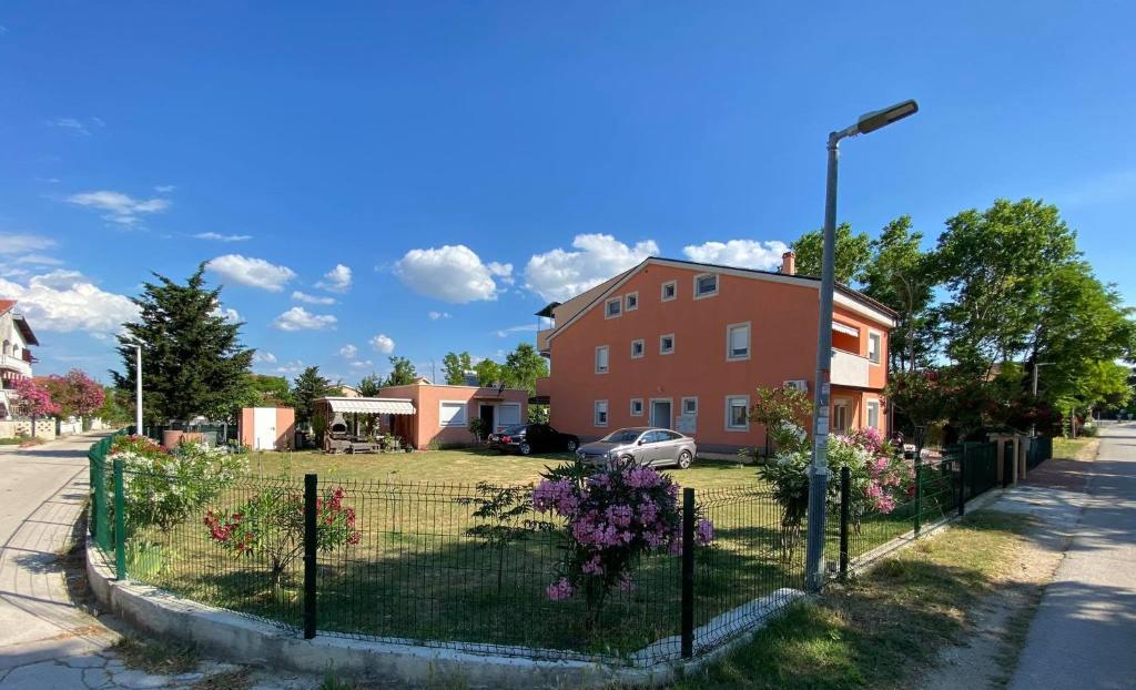 una cerca frente a una casa con flores púrpuras en Renic Apartments, en Nin