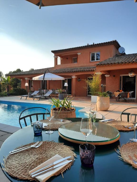 a table with wine glasses on it next to a pool at Villa Catharina in Lorgues