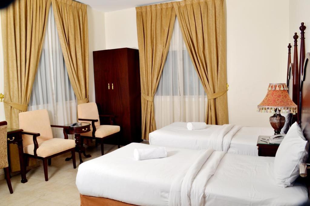 a hotel room with two beds and a table and chairs at Sara Hotel Apartments in Ajman 