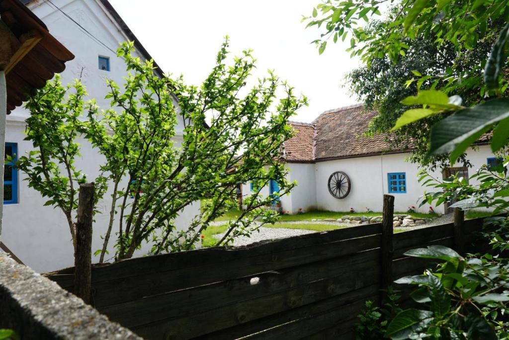 una cerca frente a una casa blanca con un reloj en La Victorel, en Porumbacu de Sus