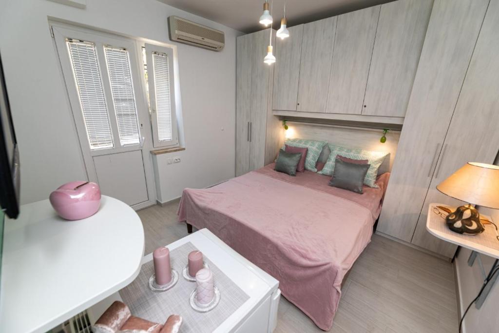 a small bedroom with a pink bed and a table at Room Gržetić in Šilo
