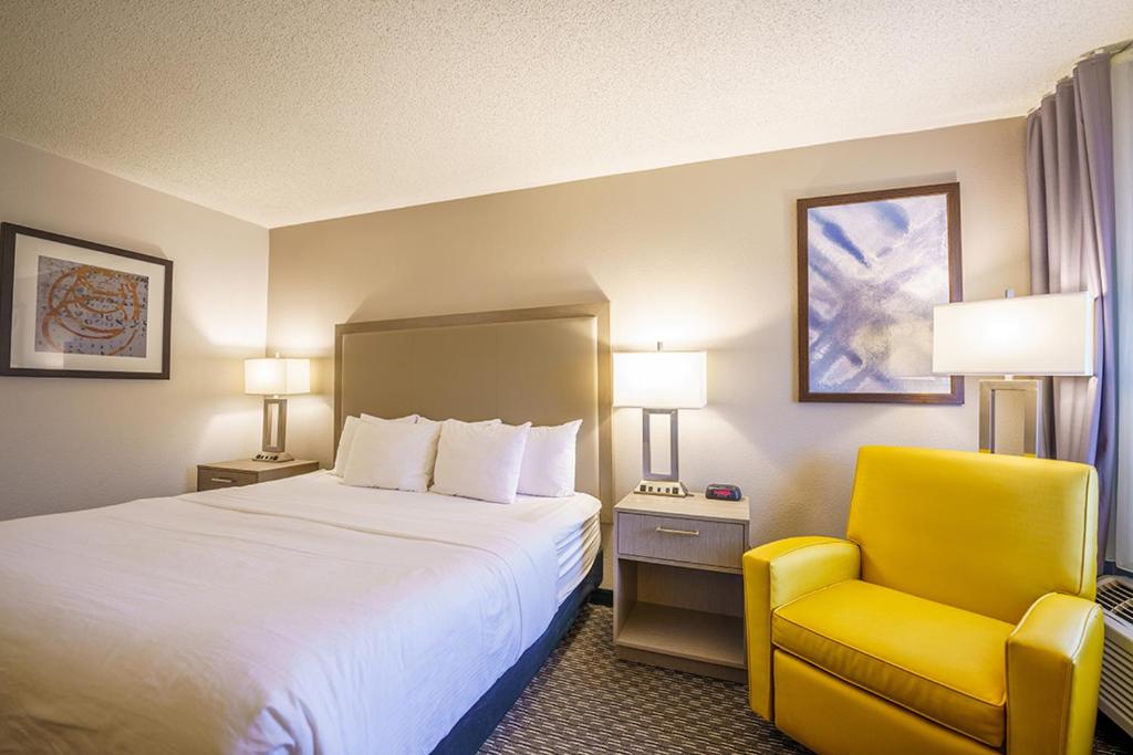 a hotel room with a bed and a yellow chair at Wingate by Wyndham Brunswick GA I-95 in Brunswick