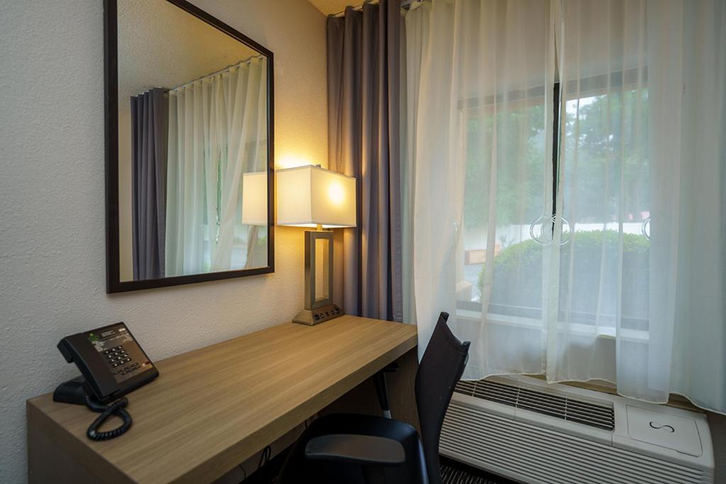 a hotel room with a desk with a phone and a window at Wingate by Wyndham Brunswick GA I-95 in Brunswick